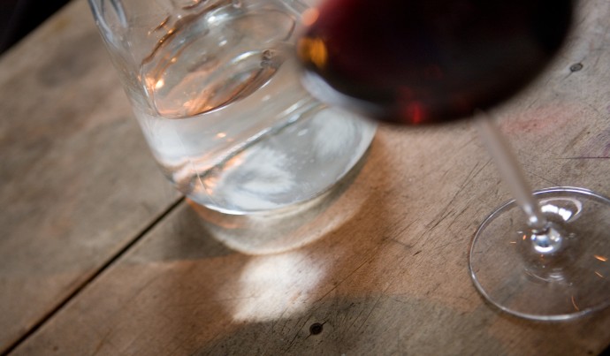 Naturwein als Rotwein in einem Glas daneben eine Karaffe Wasser