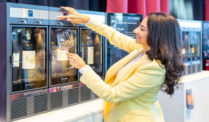 Frau entnimmt an einer Weinverkostungsstation ein Glas Wein
